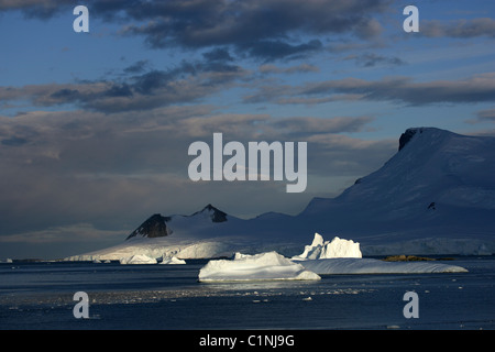 Land und sonnenbeschienenen Eisberge in [Marguerite Bay], [West Graham Land], Antarktis mit abgewinkelten Sonne und blauer Himmel Stockfoto