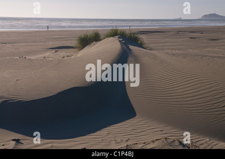 Strand Dünen mit geformten Windmuster zeigen einsame Person zu Fuß am Strand. Stockfoto