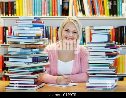 Junge Frau, umgeben von Büchern in der Bibliothek Stockfoto
