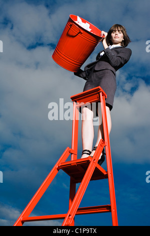 Frau wirft Müll aus dem roten bin Stand auf Leiter Stockfoto