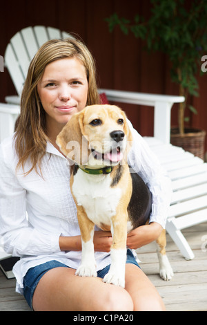 Porträt der jungen Frau mit Hund auf Veranda Stockfoto