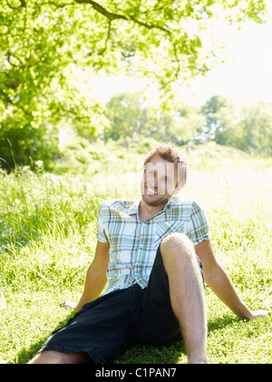 Yong-Mann auf dem Rasen sitzen und Lächeln Stockfoto