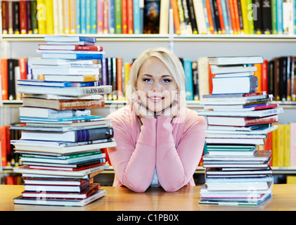 Junge Frau, umgeben von Büchern in der Bibliothek Stockfoto