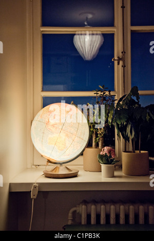 Beleuchtete Weltkugel auf Fensterbank Stockfoto