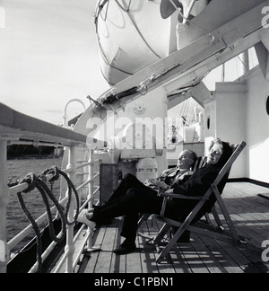 Britisch-Indien Kreuzfahrtschiff, 1950er Jahre. Am späten Abendsonne und zwei Passagiere entspannen in Liegestühlen auf der Terrasse. Stockfoto