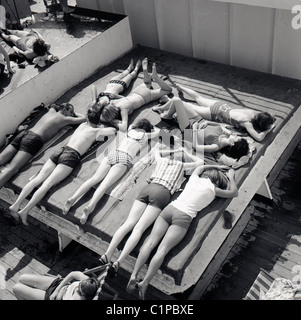 Britisch-Indien Kreuzfahrtschiff, 1950er Jahre. Gruppe von Jugendlichen, die zum Sonnenbaden auf dem Deck des Kreuzfahrtschiffes, Britisch-Indien. Stockfoto