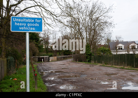 Ein Schild mit der Aufschrift "Nicht geeignet für schwere Nutzfahrzeuge" vor einem schlammigen, unbefestigten Straße Stockfoto