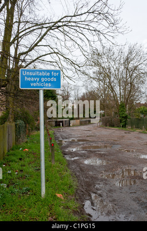 Ein Schild mit der Aufschrift "Nicht geeignet für schwere Nutzfahrzeuge" vor einem schlammigen, unbefestigten Straße Stockfoto