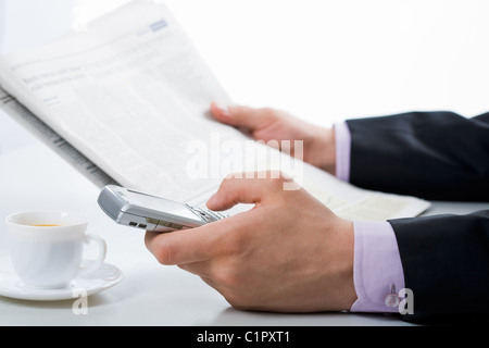 Nahaufnahme der männliche Hand, die Tasten des Smartphones beim Zeitung lesen Stockfoto