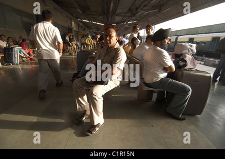 Menschen sitzen auf der Plattform am Bahnhof New Delhi, Indien. Stockfoto