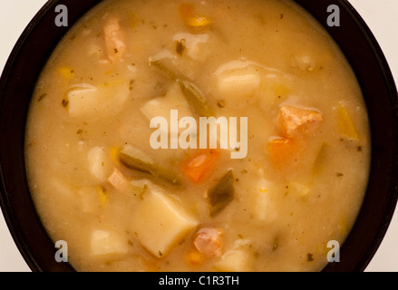 Legen Sie die Suppe mit klobigen Gemüsesuppen flach in eine schwarze Keramikschüssel. Stockfoto