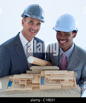 Lächelnd Ingenieure mit harte Hüte halten eines Musterhauses Stockfoto