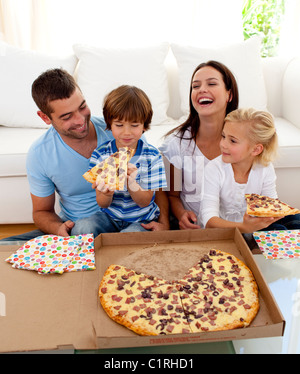 Eltern und Kinder essen Pizza im Wohnzimmer Stockfoto