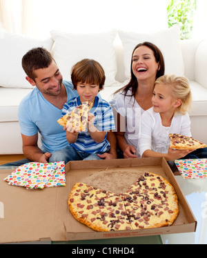 Eltern und Kinder essen Pizza im Wohnzimmer Stockfoto