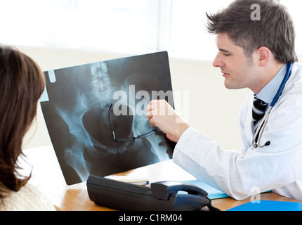 Hübscher Arzt eine Röntgenaufnahme mit einer Patientin zu analysieren Stockfoto