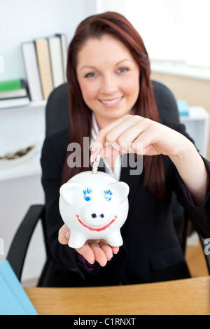 Selbstbewusste junge Geschäftsfrau, Geld in einem Sparschwein Stockfoto