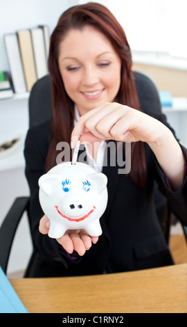 Elegante Geschäftsfrau, Geld in einem Sparschwein Stockfoto