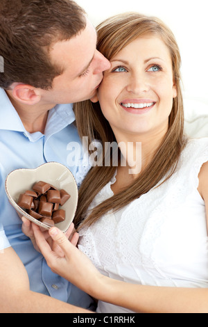 Gut aussehender Mann küsst seine Freundin hielt Chocolote sitzen Stockfoto
