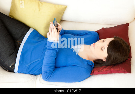 Entspannte junge Frau eine SMS auf dem sofa Stockfoto