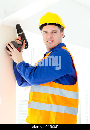 Attraktive junge Arbeiter halten ein Tool steht auf einer Leiter Stockfoto