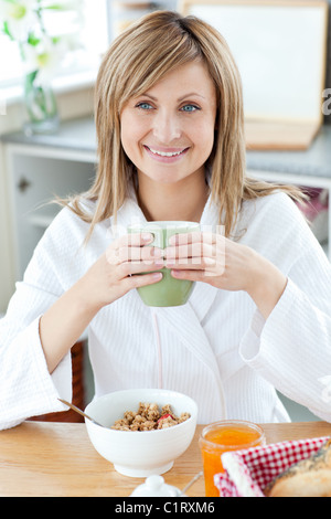 Schöne Frau mit einer Tasse Kaffee, Getreide zu Essen in der Küche Stockfoto