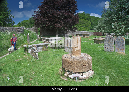 Eine Dog-Walker auf dem Friedhof der ehemaligen Benediktinerabtei in Cerne Abbas, Dorset, England, UK Stockfoto