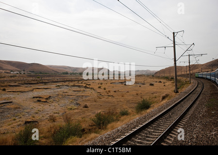 Usbekistan, Buchara, Eisenbahn und Stromleitungen laufen durch karge Landschaft Stockfoto