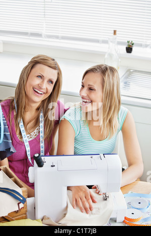 Lachende Frauen nähen Kleidung zu Hause Stockfoto