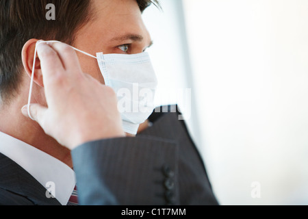 Porträt der Geschäftsmann sein Gesicht Schutzmaske aufsetzen Stockfoto