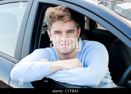 Positiven jungen Mann sitzt in seinem Auto Stockfoto