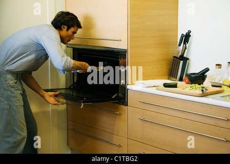 Menschen setzen Pfanne in den Ofen Stockfoto