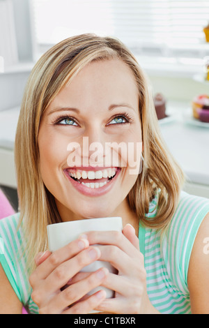 Lachende Frau hält eine Tasse Kaffee zu Hause Stockfoto