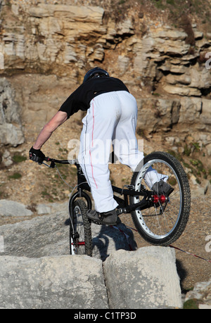 Ein junger Mann auf einem Mountainbike genießt Reiten über einige harte Felsen Stockfoto