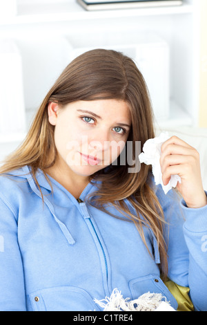 Junge Frau mit einem Gewebe im Wohnzimmer sitzen Stockfoto