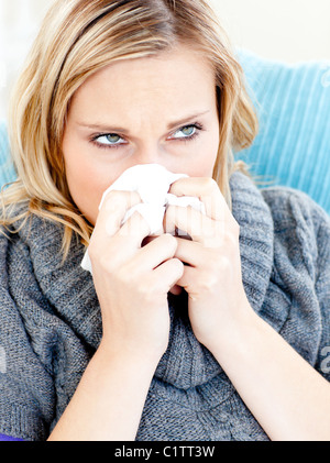 Niedergeschlagenen Frau auf einem Sofa liegend mit Gewebe und bläst Stockfoto
