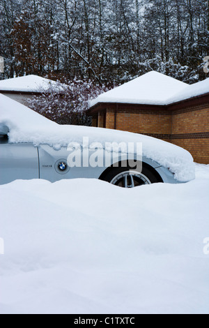 SPORT AUTO STECKEN AUßEN HAUS IN STARKEM SCHNEEFALL Stockfoto