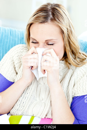 Kranke Frau auf einem Sofa liegend mit Gewebe und bläst Stockfoto