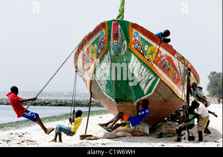 jungen schwingen auf einem Angeln Boot am Strand von Dakar, Senegal Stockfoto