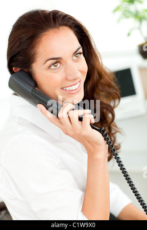 Attraktive junge Geschäftsfrau, die am Telefon sitzt an ihrem Schreibtisch Stockfoto