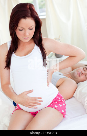 Porträt einer schönen schwangeren Frau sitzt auf Bett Stockfoto