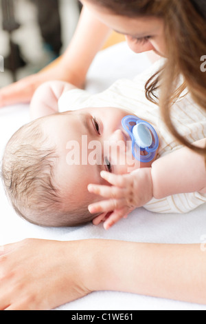 Nahaufnahme eines Babys auf einen Wickeltisch liegend, während seine Mutter seine Windel ändert Stockfoto