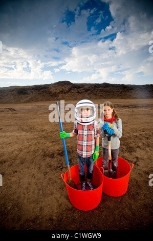 Junge Astronaut stehend mit einem Mädchen in Eimern zu imitieren Stockfoto
