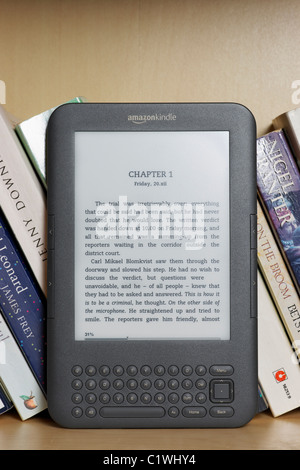 Ein Amazon Kindle Ebook Reader auf einem Bücherregal mit Taschenbüchern. Dies ist das Kindle 3-Modell.  NUR ZU REDAKTIONELLEN ZWECKEN Stockfoto