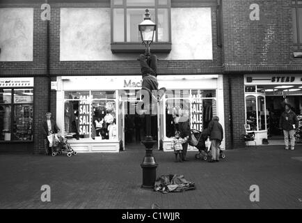 Straße Entertainer Flötenspiel, während hängen von einer Lampe Post, Lewes, Sussex, England Stockfoto