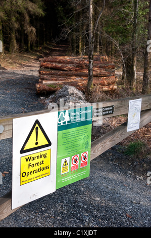 Hinweise auf ein Tor in eine Forstverwaltung Wald Warnung der Abholzung in der Gegend, mit einem Stack von frisch geschnittenen Protokolle Stockfoto