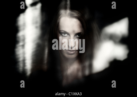 Zauberin aus hinter dem dunklen Glas mit Reflexionen Stockfoto