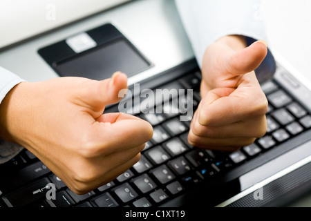 Nahaufnahme der weiblichen Hände mit Daumen hoch über Laptop-Tastatur am Arbeitsplatz Stockfoto