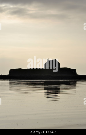 St Cwyfans Kirche aus dem 13. Jahrhundert, als die Sonne in der Nähe von aberffraw auf Anglesey an der Küste von Nordwales setzt Stockfoto