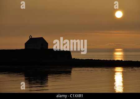 St Cwyfans Kirche aus dem 13. Jahrhundert, als die Sonne in der Nähe von aberffraw auf Anglesey an der Küste von Nordwales setzt Stockfoto