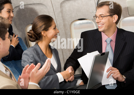 Foto von Handshaking hübsche Frau mit schönen Partner nach dem Auftreffen auf Deal im Flugzeug Stockfoto